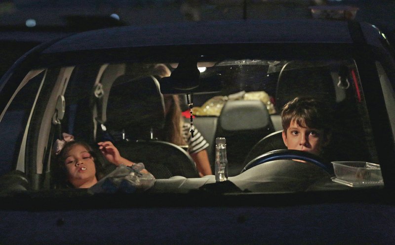 Children watch a film from inside their car May 23 at a drive-in movie theater in Brasilia, Brazil. Movie-goers bring popcorn and snacks from home. (AP/Eraldo Peres)