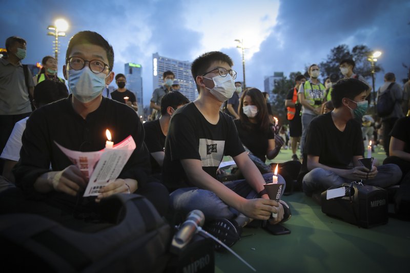 Hong Kong democracy activist Joshua Wong, center, holds a candle as he joins others for a vigil to remember the victims of the 1989 Tiananmen Square Massacre at Victoria Park in Causeway Bay, Hong Kong, Thursday. China is tightening controls over dissidents while pro-democracy activists in Hong Kong and elsewhere try to mark the 31st anniversary of the crushing of the pro-democracy movement in Beijing's Tiananmen Square. - AP Photo/Kin Cheung