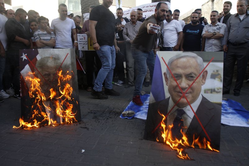Palestinians burn pictures of U.S. President Donald Trump, left, and Israeli Prime Minister Benjamin Netanyahu during a protest against Trump's mideast initiative, in the West Bank city of Nablus, Saturday, May 30, 2020.(AP Photo/Majdi Mohammed)