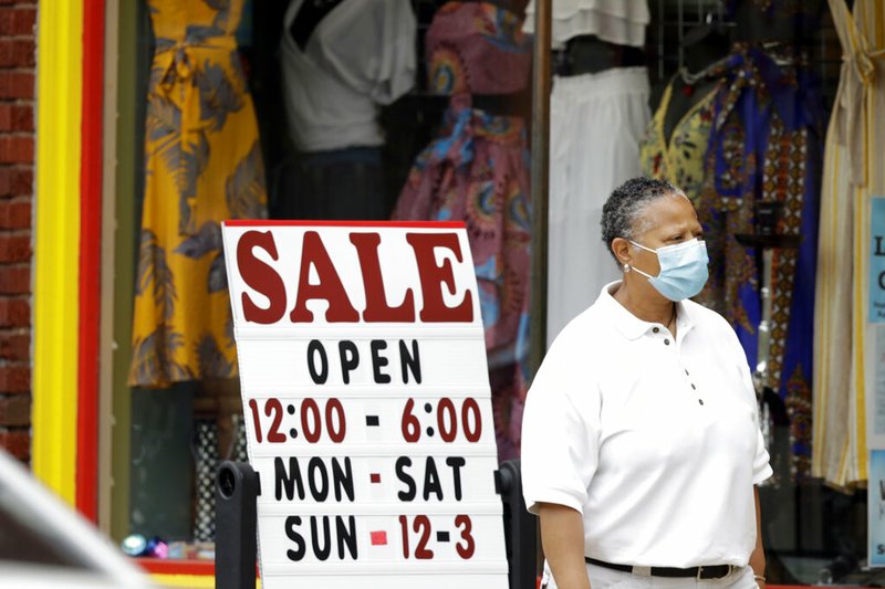 A woman walks past a boutique with a sale sign, Thursday, June 4, 2020, in Cleveland Heights, Ohio.