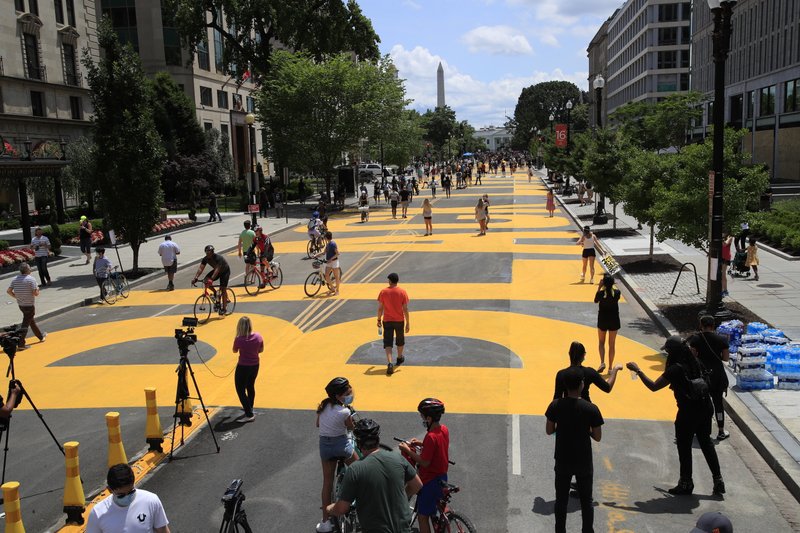 With the Washington Monument in the background, people walk on the street leading to the White House after the words Black Lives Matter were painted on it by city workers and activists on June 6 in Washington. - AP Photo/Manuel Balce Ceneta