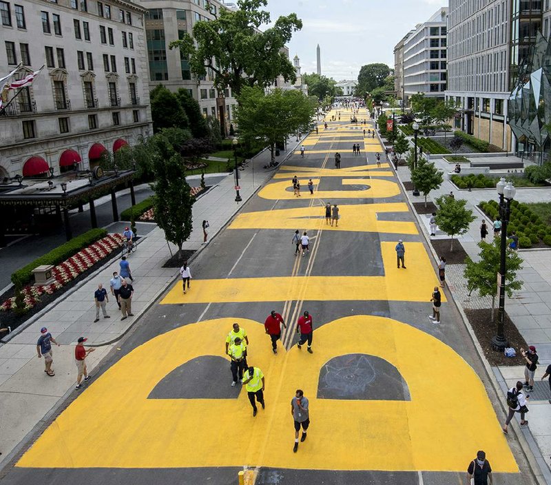 The words Black Lives Matter cover a section of 16th Street in Washington near the Washington Monument and the White House. City workers and activists painted the bright yellow letters together. More photos at arkansasonline.com/66paint/.
(AP/Executive Office of the Mayor/Khalid Naji-Allah)