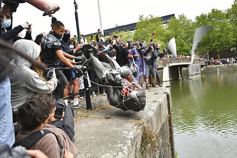 Protesters throw a statue of slave trader Edward Colston into Bristol Harbor during a Black Lives Matter protest rally in Bristol, England, on Sunday, June 7, 2020. The statue was torn down in response to the recent killing of George Floyd by police officers in Minneapolis.