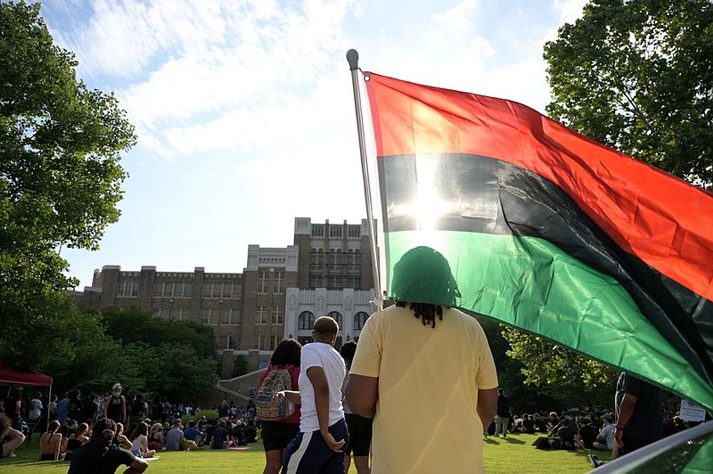 Hassan Bey stands with the Pan-African flag Sunday during a pro- test at Central High School in Little Rock. More photos at arkan- sasonline.com/68lrprotest/. (Arkansas Democrat-Gazette/Stephen Swofford 
