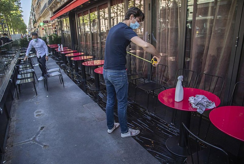 Pierre-Antoine Boureau uses a tape measure as he prepares the terrace of a restaurant in order to respect distancing to help curb the spread of the coronavirus in Paris, last week.
(AP/Michel Euler)