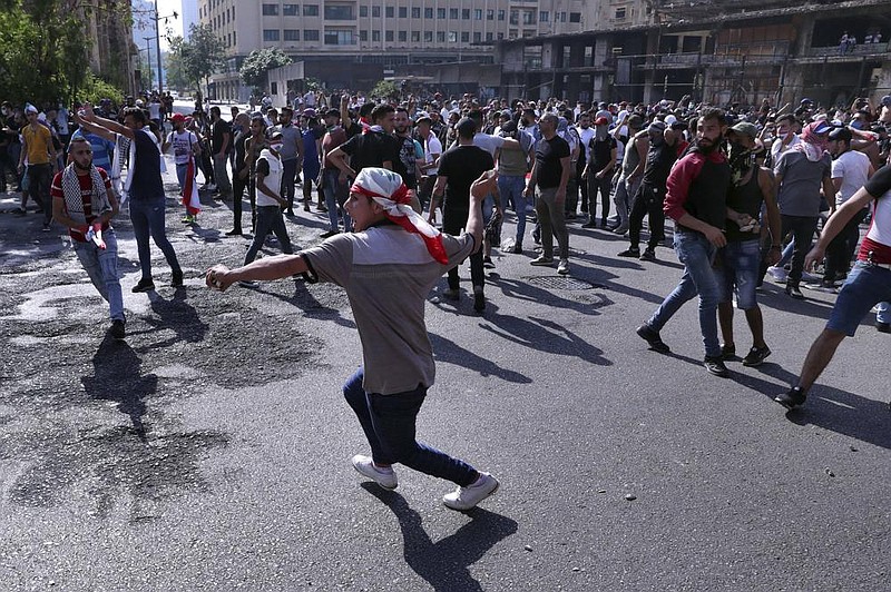 A Lebanese anti-government protester throws a rock at riot police Saturday in downtown Beirut. More photos at arkansasonline.com/67lebanon/.
(AP/Bilal Hussein)