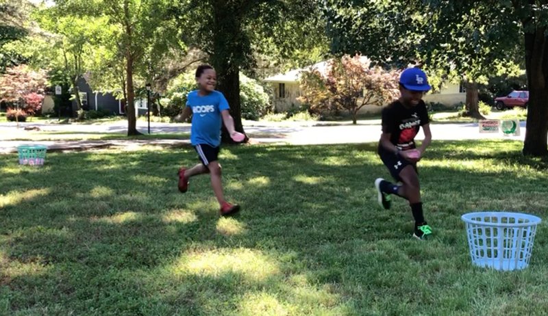 Angela Duran and her boys Noah, 7, and Matthew, 9, play the Water Balloon Race. The boys race to a basket of water balloons and carry them one by one to another basket near Duran, who counts how many each child delivers. When Matthew wins with six, he takes one free shot at Noah. He misses. And then it's a free-for-all, all over the yard. (Arkansas Democrat-Gazette/Celia Storey)