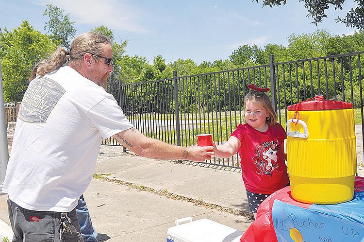 Customer Tim Hannon gets a cup of lemonade from Ryleigh Gilliam on Main Street in Noel. She set up a lemonade stand on May 30 to benefit the McDonald County Senior Center and raised $201, much of which was donations.