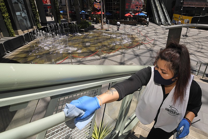 In this Thursday, June 11, 2020 file photo, Andrea Castaneda cleans the railings at Universal CityWalk near Universal City, Calif. (AP Photo/Mark J. Terrill)