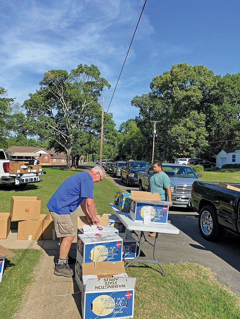 Dennis James, left, from Plummerville United Methodist Church and Ethan Black from Mount Carmel Missionary Baptist Church work together to hand out food donations during a recent drive-thru ministry at Plummerville UMC. Pastor Patti Butler of Plummerville UMC said that since the pantry began, volunteers have distributed more than 900 boxes of food items.