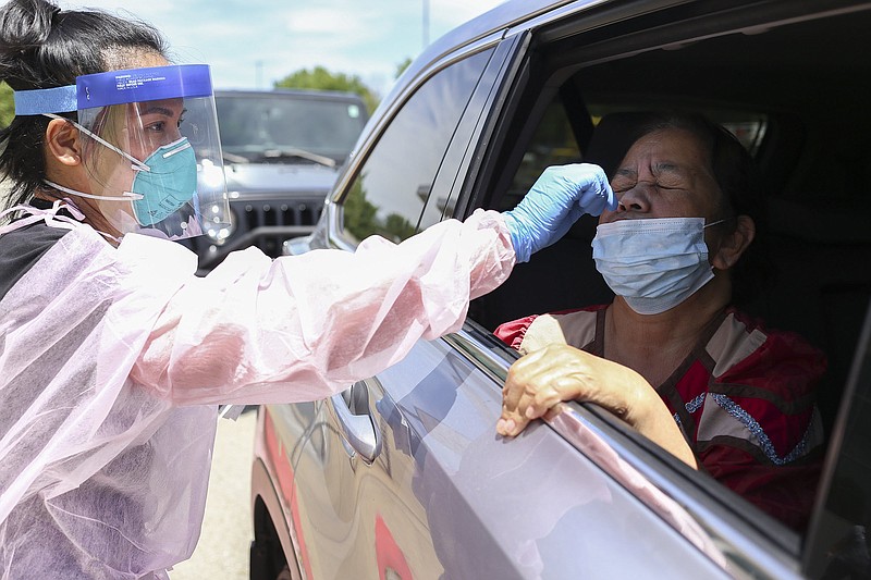 Nurse Ruby Lewis (from left) administers a covid-19 test to Laling Riklon of Springdale, Saturday, May 23, 2020 at the Center for Nonprofits parking lot in Springdale. The Arkansas Department of Health partnered with the Arkansas Coalition of Marshallese to host a drive-thru covid-19 testing site. Volunteers also distributed groceries and masks to those waiting in line. (NWA Democrat-Gazette/Charlie Kaijo)

