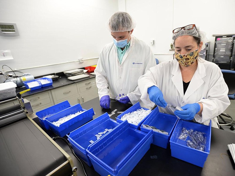 Mason Blaschke, (left) and Gabriella Miller work together Thursday assembling covid-19 antibody tests at NOWDiagnostics in Springdale. (NWA Democrat-Gazette/Andy Shupe) 