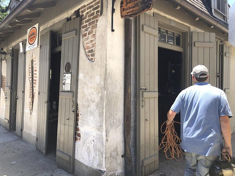 A worker carries equipment Friday into Lafitte’s Blacksmith Shop, a bar on Bourbon Street in New Orleans. More photos at arkan- sasonline.com/614orleans/. (AP/Kevin McGill) 