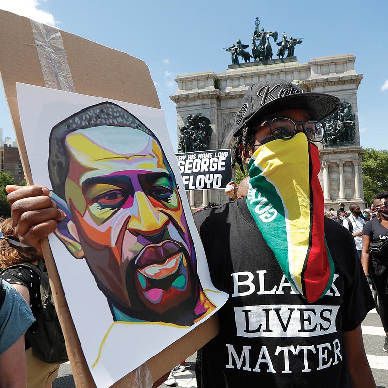 A man holds up an image of George Floyd and wears a Guyanese flag as face protection Sunday during a rally led by Caribbean Americans at Grand Army Plaza in the Brooklyn borough of New York. More photos at arkansasonline.com/615floyd/. 
(AP/Kathy Willens) 