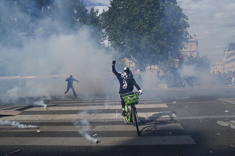 A cyclist rides through a cloud of tear gas Saturday in Paris during a march against racism and police brutality. More photos at arkansasonline.com/615france/. (AP/Thibault Camus) 