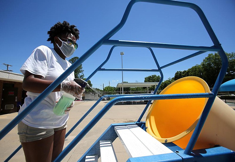 Lifeguard Chelsea Smith, 19, sanitizes the railing of a slide between pool sessions Thursday at the North Heights Community Center in North Little Rock. Video at arkansasonline.com/615pool/. (Arkansas Democrat-Gazette/Thomas Metthe) 
