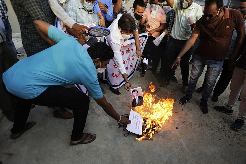 An Indian man burns a photograph of Chinese president Xi Jinping during a protest against China in Ahmedabad, India, Tuesday, June 16, 2020. At least three Indian soldiers, including a senior army officer, were killed in a confrontation with Chinese troops along their disputed border high in the Himalayas where thousands of soldiers on both sides have been facing off for over a month, the Indian army said Tuesday.