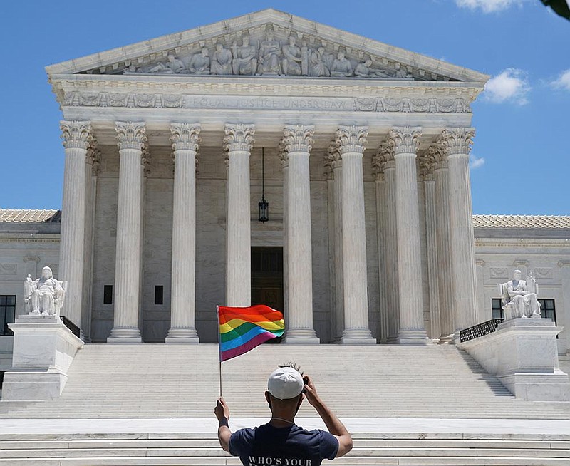 A person waves a rainbow flag, a symbol of LGBTQ pride, on Mon- day in front of the Supreme Court building in Washington. (The New York Times/Anna Moneymaker) 