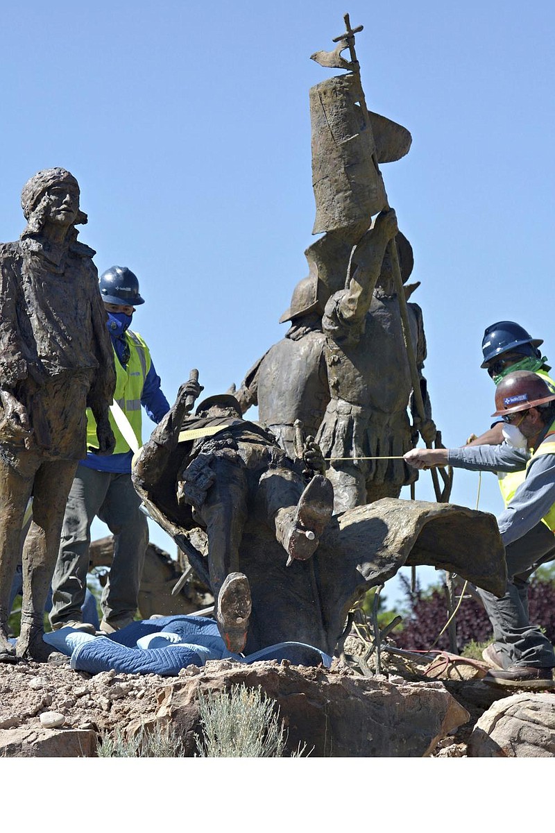 Workers remove the statue of Spanish explorer Juan de Onate on Tuesday outside the Albuquerque Museum in New Mexico. More photos at arkansasonline.com/617nm/. (AP/The Albuquerque Journal/Jim Thompson) 