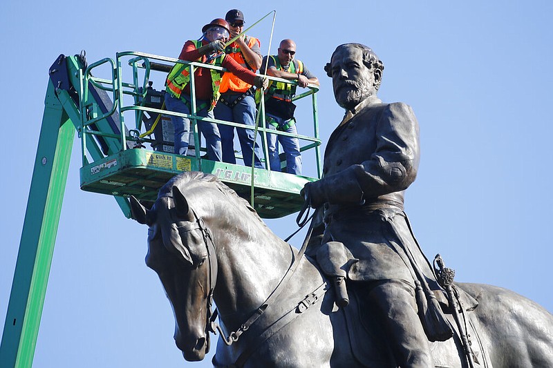 An inspection crew from the Virginia Department of General Services takes measurements as they inspect the statue of Confederate Gen. Robert E. Lee on Monument Avenue in Richmond, Va., in this June 8, 2020, file photo.