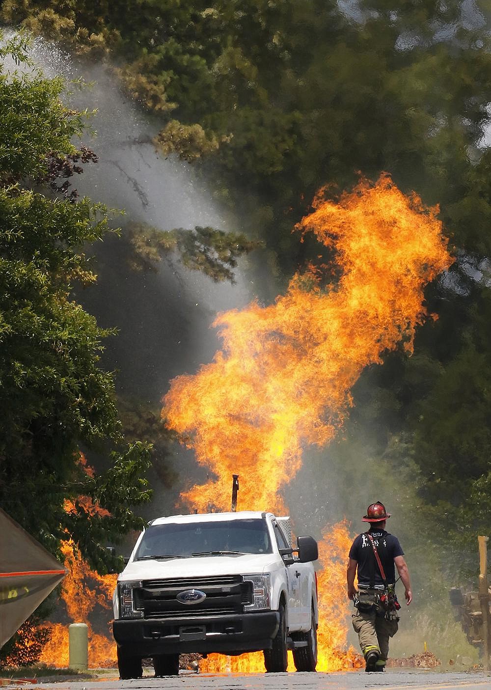 Firefighters approach a gas main fire that erupted Thursday afternoon in Maumelle. Two men were reportedly injured in the initial explosion, which occurred near the intersection of Edgewood Drive and Windwood Lane, across the street from the Jess Odom Community Center. More photos at arkansasonline.com/619gasfire/.
(Arkansas Democrat-Gazette/John Sykes Jr.)