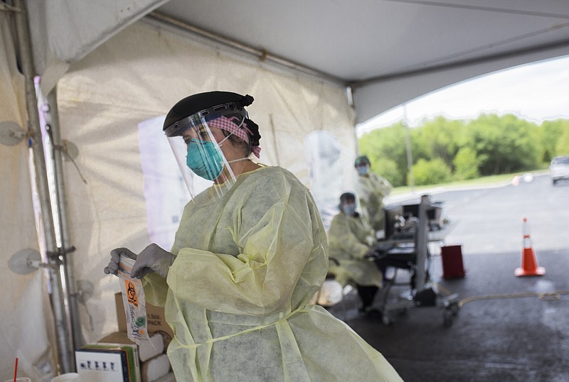 FILE -- Nurse Caitlin Percival bags a covid-19 test, Friday, April 24, 2020 at a drive-thru testing site at the Mercy Convenient Care in Bentonville.
(NWA Democrat-Gazette/Charlie Kaijo)