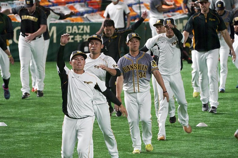 Hanshin Tigers players warm up before a game against the Yomiuri Giants on Friday at Tokyo Dome in Tokyo. Japan opened its professional regular season Friday without fans in attendance.
(AP/Eugene Hoshiko)