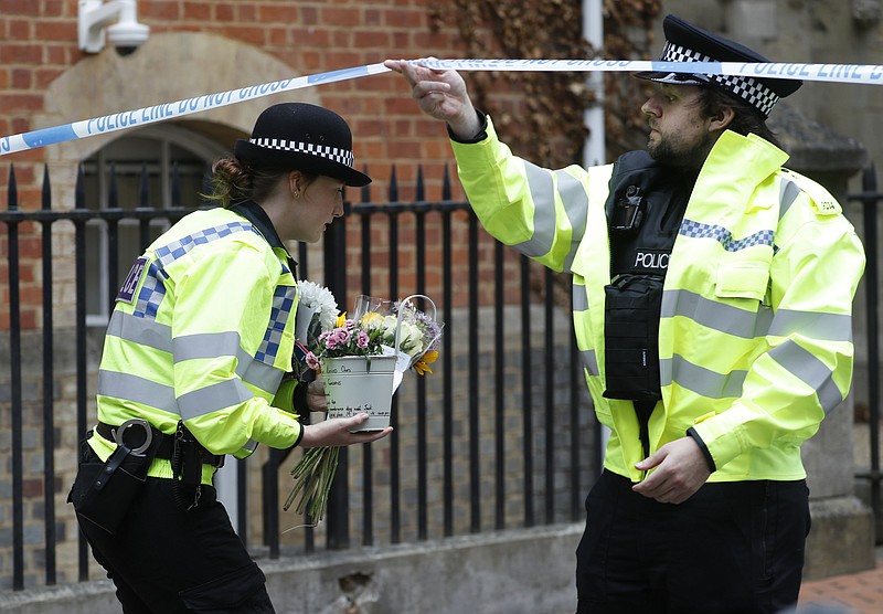 Police officers on Sunday collect flowers left at the Abbey Gateway of Forbury Gardens after the attack in Reading, England. More photos at arkansasonline.com/622reading/. (AP/Alastair Grant) 
