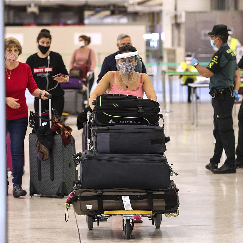 Passengers arrive Sunday at Adolfo Suarez Madrid-Barajas Airport in Spain. The country opened its borders to European tourists on Sunday in an effort to kickstart its economy. More photos at arkan- sasonline.com/622covid/. (AP/Bernat Armangue) 
