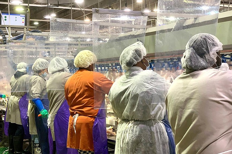 Tyson Foods workers wear protective gear and stand between plastic dividers at the company’s Camilla, Ga., poultry processing plant in this April photo provided by the Springdale-based company. (AP) 