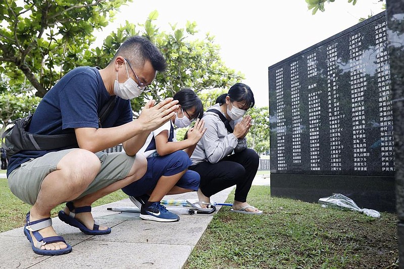 A family prays Tuesday in front of a monument at Peace Memorial Park in Itoman on the island of Okinawa. The monument lists the names of civilians and service members of all nationalities who died in the Battle of Okinawa during World War II. More photos at arkansasonline.com/624war/. 
(AP/Kyodo News) 
