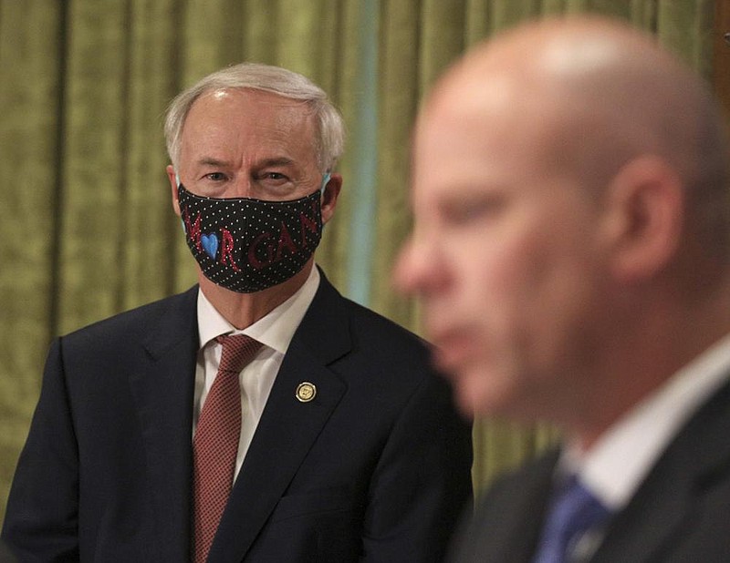 Gov. Asa Hutchinson, left, listens to Troy Wells, president and CEO of Baptist Health speak Monday June 22, at the state Capitol in Little Rock during the governor’s daily COVID-19 briefing. (Arkansas Democrat-Gazette/Staton Breidenthal)