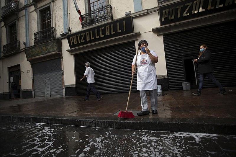 A worker cleans the sidewalk in front of a restaurant in Mexico City early this month. The International Monetary Fund is forecasting a nearly double-digit recession for Latin America and the Caribbean this year. Video is available at arkansasonline.com/625fund/.
(AP/Fernando Llano)