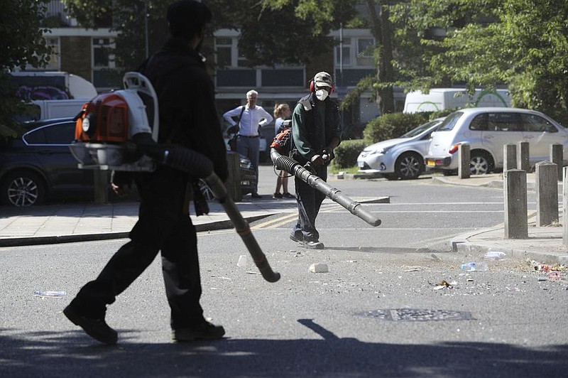 Volunteers clean up the streets Thursday after overnight clashes between street-party revelers and police in the Brixton area of London.
(AP/Jonathan Brady)