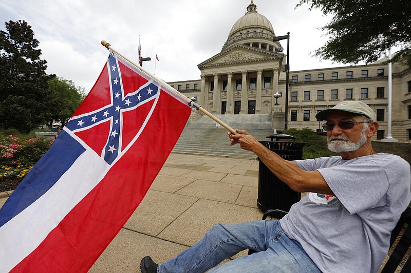 Larry Eubanks of Star, Miss., waves the current Mississippi state flag as he sits in front of the state Capitol at Jackson, Miss., on Saturday, June 27, 2020. Eubanks supports the current Mississippi state flag, which includes the design of the Civil War-era Confederate battle flag, but he says he hopes lawmakers would allow a proposed flag change to be decided by registered voters.