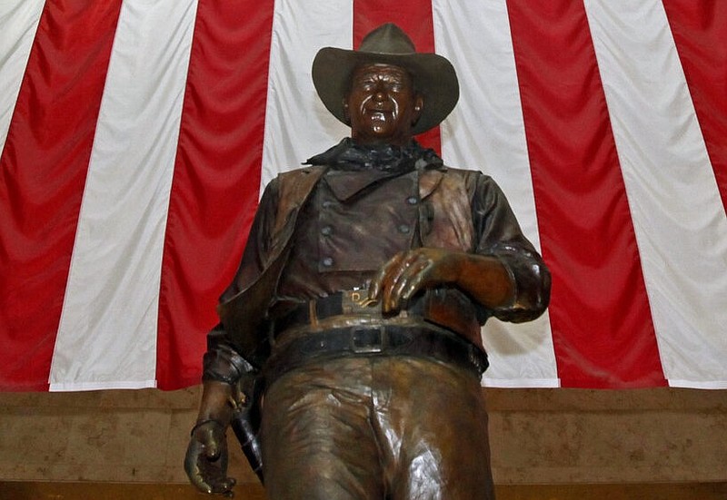 A bronze statue of the late actor John Wayne stands before a four-story U.S. flag at John Wayne Orange County Airport in Santa Ana, Calif., in this Sept. 11, 2011, file photo.