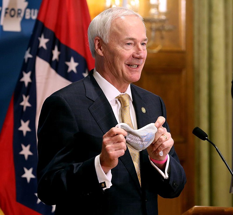 Gov. Asa Hutchinson shows off his Museum of Discovery mask he was wearing for a COVID-19 briefing on Friday, June 26, at the state Capitol in Little Rock. (Arkansas Democrat-Gazette/Thomas Metthe) story.lead_photo.caption