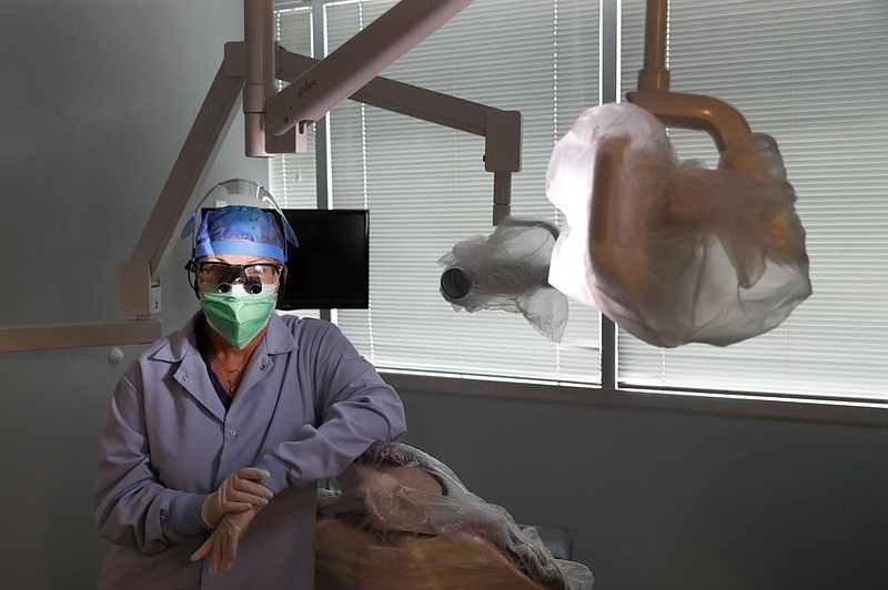 Dr. Terri Tiersky poses for a portrait in full personal protective equipment, double mask, face shield, gown and gloves, at her dentist office in Skokie, Ill., earlier this month. (AP/Charles Rex Arbogast) 