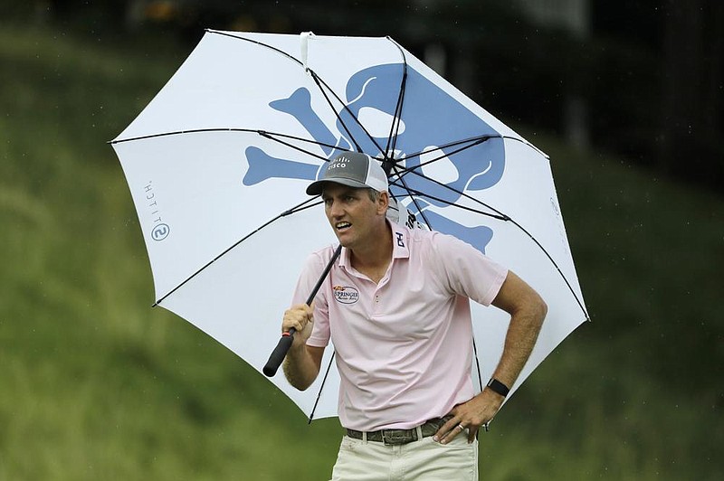 Brendon Todd looks at a competitor’s tee shot while sheltering from the rain with an umbrella on the 18th hole during the third round of the Travelers Championship on Saturday at TPC River Highlands in Cromwell, Conn. Todd fired a career-low 61, matching Dustin Johnson, to take a two-stroke lead into today’s final round.
(AP/Frank Franklin II) story.lead_photo.caption