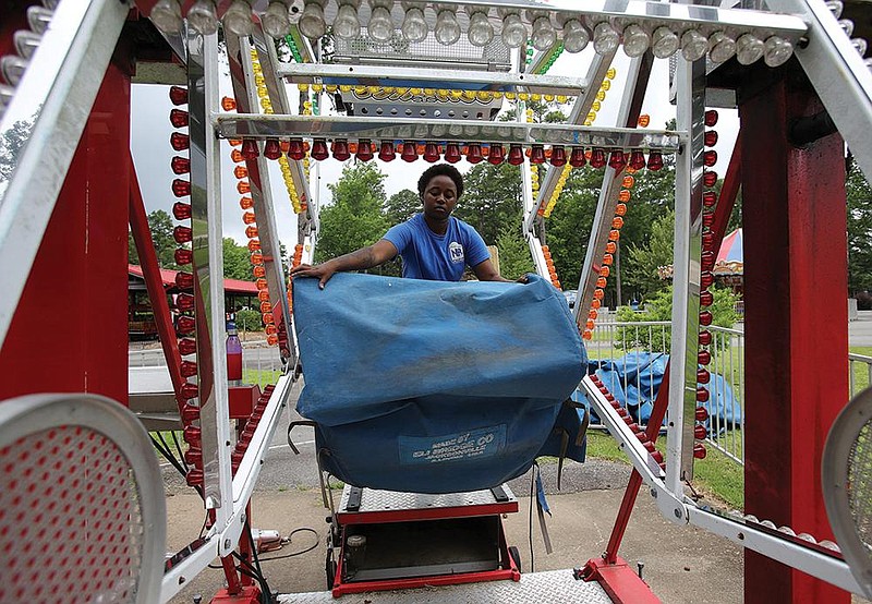 Dajsamone Johnson pulls the seat covers off the Ferris wheel ride at Funland before opening on Friday at Burns Park in North Little Rock. Funland is open Fridays 1 p.m. to 7 p.m., Saturdays 10 a.m. to 7 pm and Sundays 1 p.m. to 6 p.m. (Arkansas Democrat-Gazette/Thomas Metthe) 
