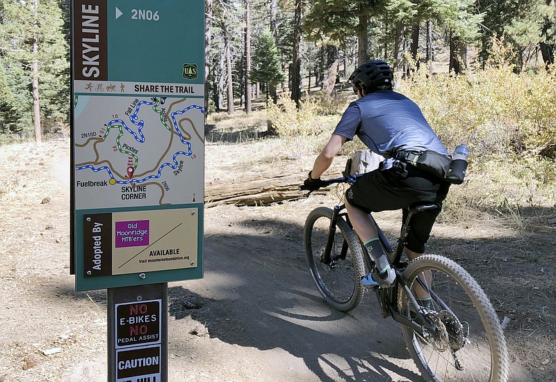 FILE -- In this photo taken Sept. 23, 2018, a mountain biker pedals past a No E-bikes sign in the San Bernardino National Forest near Big Bear Lake, Calif. (AP Photo/Brian Melley)