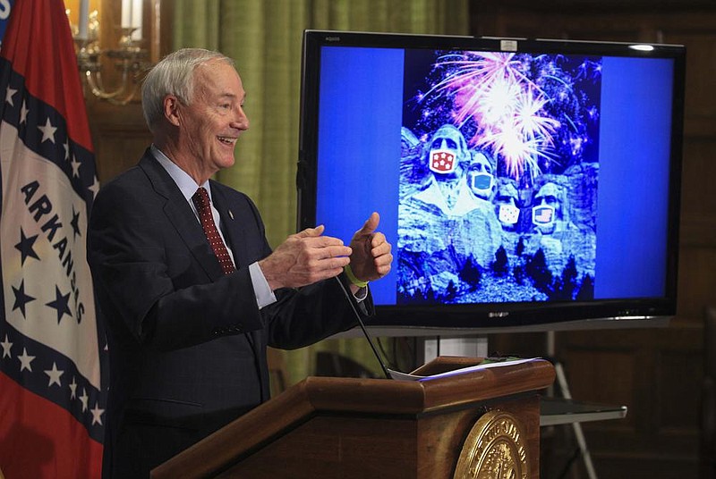 Gov. Asa Hutchinson speaks Tuesday June 30 at the state Capitol in Little Rock during his daily COVID-19 briefing about the importance of wearing a mask this holiday weekend as he shows an image of the presidents at Mt. Rushmore with wearing masks. (Arkansas Democrat-Gazette/Staton Breidenthal)