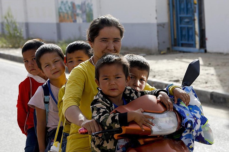 A Uighur woman and children sit on a motorized tricycle at the Unity New Village in Hotan, China, in this September 2018 photo. Birth rates in the mostly Uighur regions of Hotan and Kashgar dropped by more than 60% from 2015 to 2018, government statistics show. (AP/Andy Wong) 