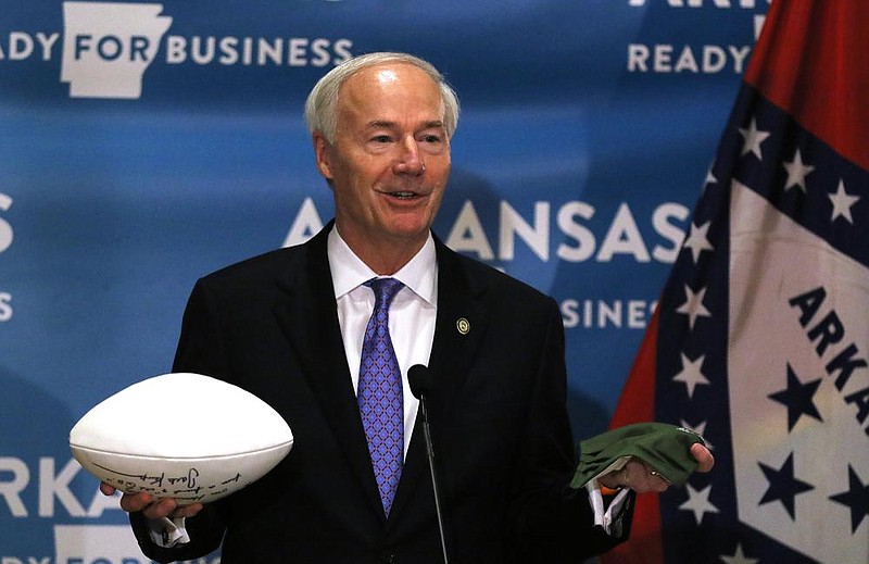 Gov. Asa Hutchinson holds a football in one hand and a mask in the other to emphasize the need to control the spread of the coronavirus. “There’s a connection between the two,” he said. “We wear our masks, we reduce the cases, we reduce the growth, we stop the spread of the virus, and that puts us in a better position to have some type of team sports this fall.”
(Arkansas Democrat-Gazette/Thomas Metthe)
