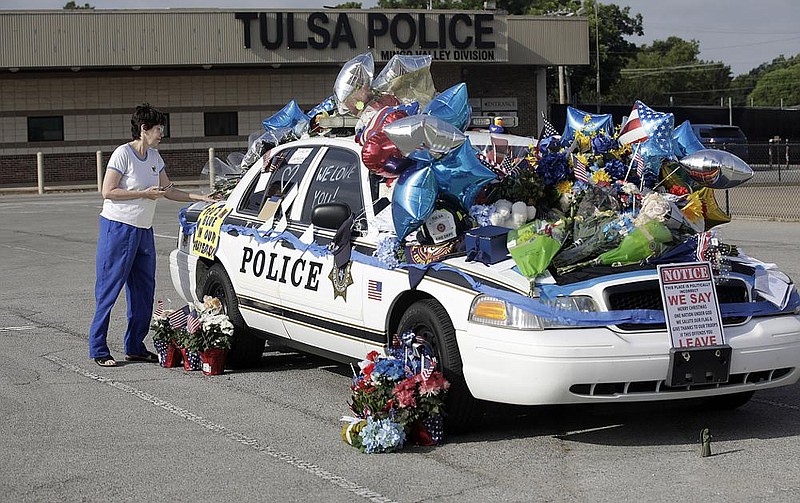 Melanie Dickey, a registered nurse, places an item on a make- shift memorial Tuesday for Tulsa police officers Craig Johnson and Aurash Zarkeshan who were shot Monday morning during a traffic stop. 
(AP/Tulsa World/Mike Simons) 