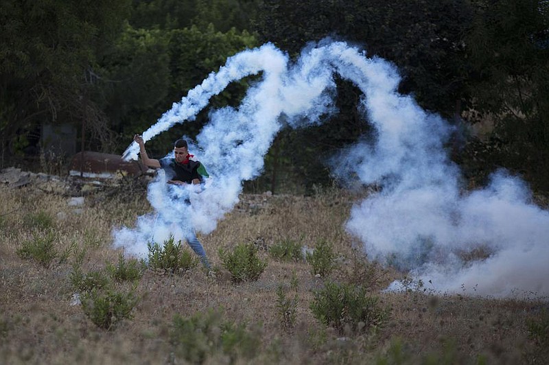 Near the Israeli settlement of Bet El, north of Ramallah, a demonstrator throws back a tear gas canister Wednesday fired by Israeli forces during clashes as Palestinians protest Israel’s plan to annex parts of the West Bank.
(AP/Majdi Mohammed)