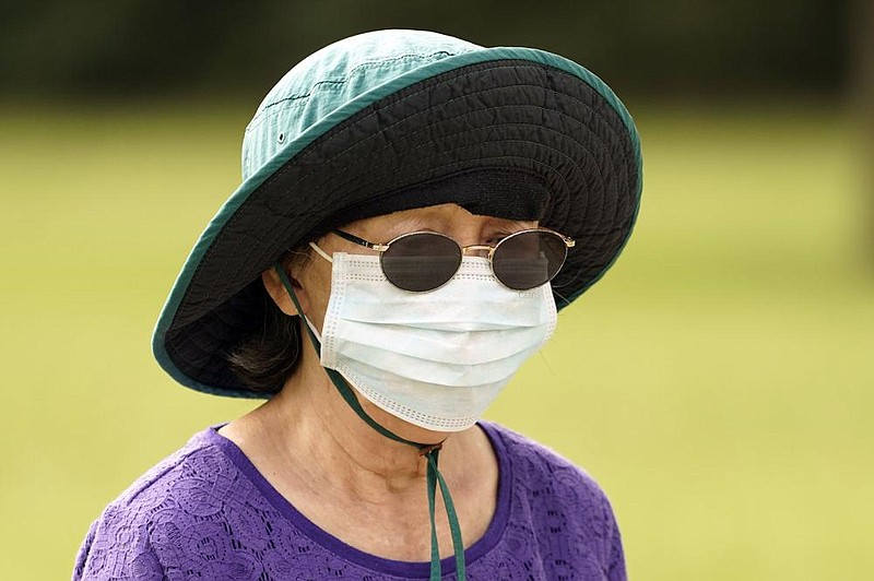 A woman covers up while walking in a park Wednesday in Houston, where the number of people hospitalized in intensive care continues to rise.
(AP/David J. Phillip