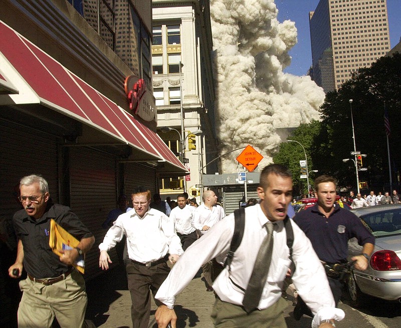 People run from the collapse of one of the twin towers of the World Trade Center in New York in this Sept. 11, 2001, file photo. Stephen Cooper (far left), who fled smoke and debris as the south tower crumbled just a block away from where this photo was taken, has died from coronavirus, his family said, according to The Palm Beach Post.