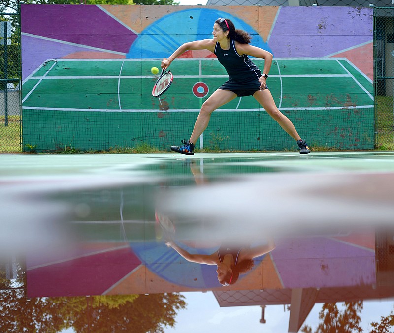 Morgan Scholz of Fayetteville is reflected in a puddle of water Saturday as she returns a shot while playing tennis with a partner in Wilson Park in Fayetteville. Scholz and her partner are new to the game and were taking advantage of a cool morning and empty courts to practice. “It’s great that we’re learning together,” Scholz said. Visit nwaonline.com/200704Daily/ for today’s photo gallery.

(NWA Democrat-Gazette/Andy Shupe)