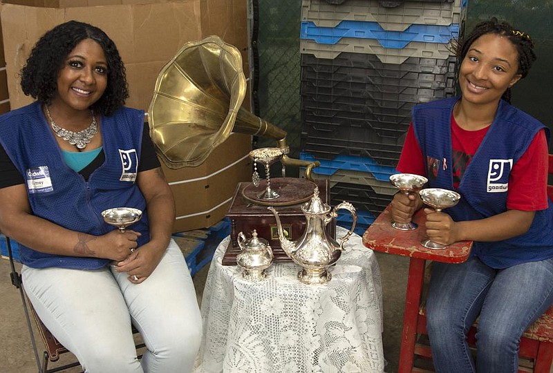 Courtney Piggee and Maliyah Reynolds show some of the treasures they unearthed among goods donated to Goodwill Industries of Arkansas. Their favorite finds include an antique spinning wheel and a silver loving-cup trophy.
(Arkansas Democrat-Gazette/Cary Jenkins)